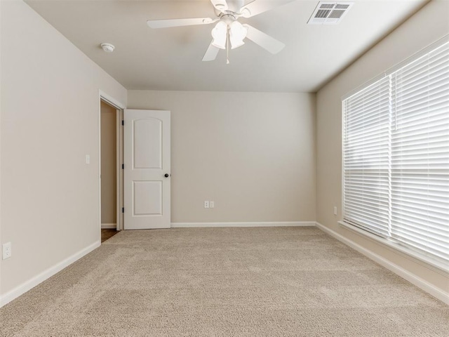 empty room featuring a ceiling fan, carpet, visible vents, and baseboards