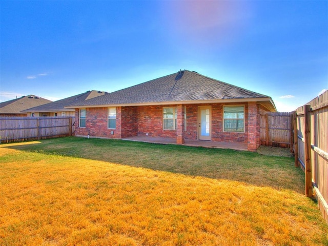 back of house with a yard, brick siding, a patio area, and a fenced backyard