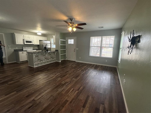 unfurnished living room featuring dark wood finished floors, baseboards, visible vents, and a textured ceiling