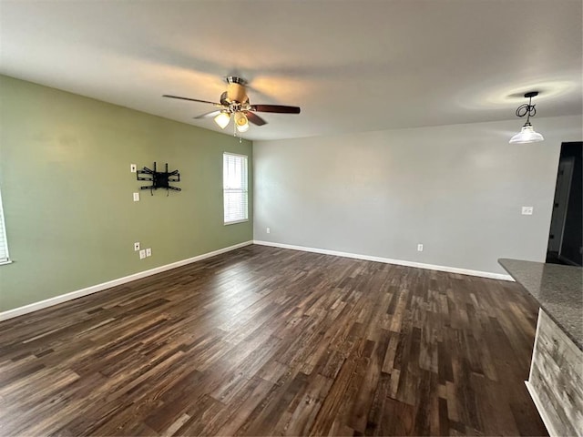 unfurnished living room featuring dark wood-type flooring, baseboards, and ceiling fan