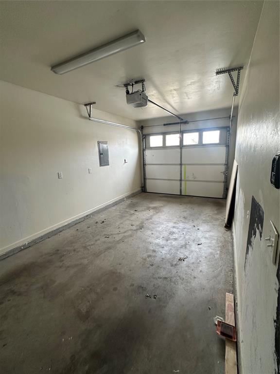 garage with electric panel, baseboards, and a garage door opener