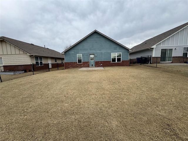 back of house featuring a lawn, brick siding, and a fenced backyard