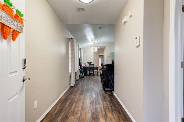 hall featuring dark wood-style floors, baseboards, visible vents, and vaulted ceiling