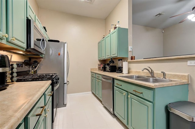 kitchen with stainless steel appliances, light countertops, a ceiling fan, a sink, and green cabinetry