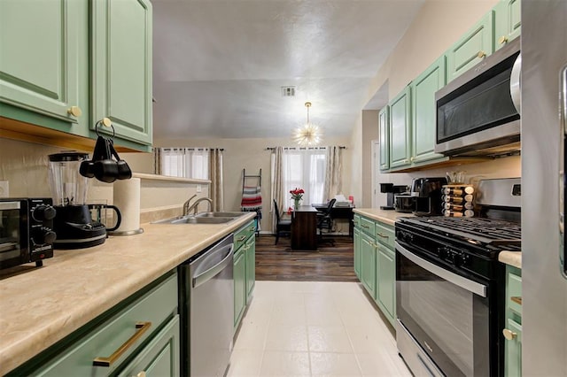 kitchen featuring appliances with stainless steel finishes, a sink, visible vents, and green cabinetry