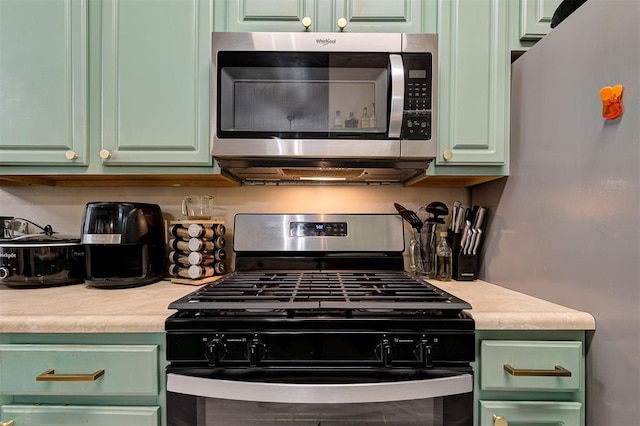 kitchen featuring stainless steel appliances, light countertops, and green cabinets