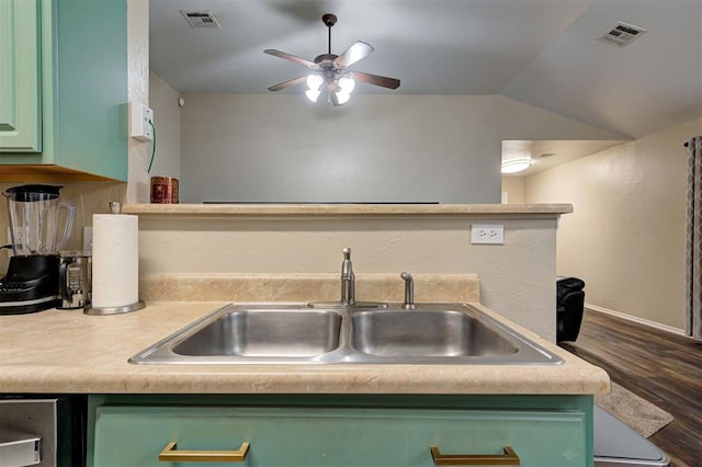 kitchen with lofted ceiling, visible vents, green cabinets, and a sink