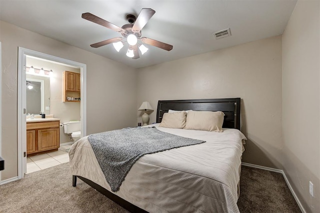 bedroom featuring baseboards, visible vents, connected bathroom, light colored carpet, and ceiling fan