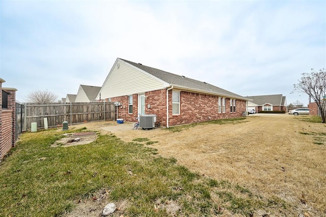 exterior space featuring a fire pit, a lawn, fence, central AC, and brick siding