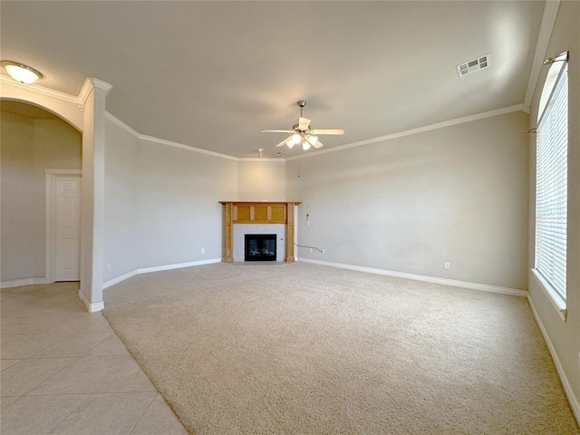 unfurnished living room featuring arched walkways, crown molding, visible vents, a glass covered fireplace, and light carpet