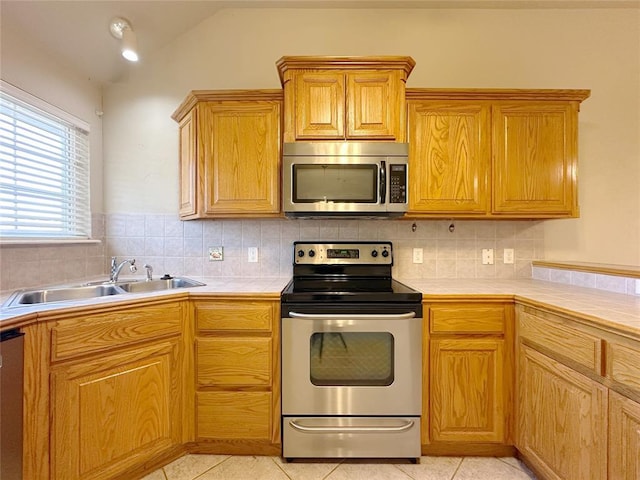 kitchen featuring a sink, appliances with stainless steel finishes, tile counters, and light tile patterned flooring