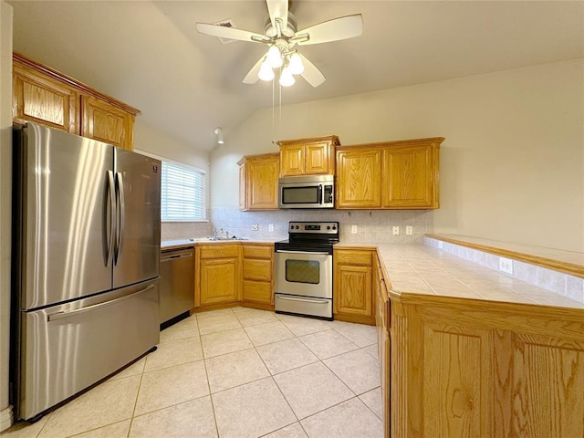 kitchen featuring light tile patterned floors, stainless steel appliances, backsplash, and tile counters