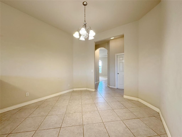 unfurnished room featuring light tile patterned floors, baseboards, arched walkways, and a chandelier