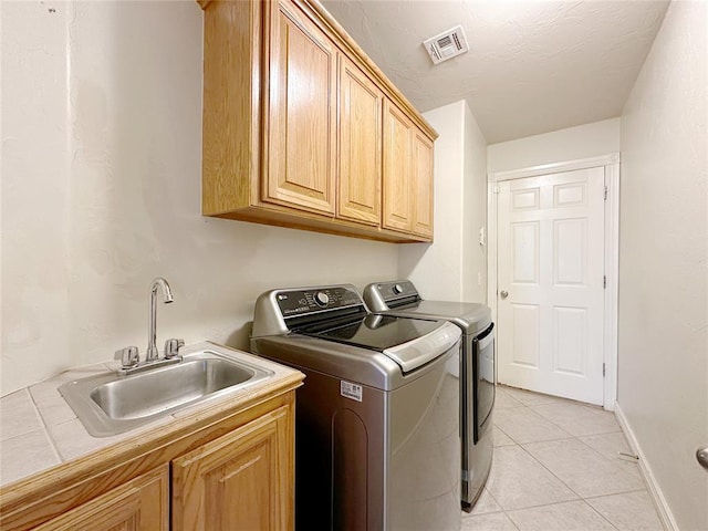 clothes washing area featuring cabinet space, visible vents, washing machine and dryer, a sink, and light tile patterned flooring