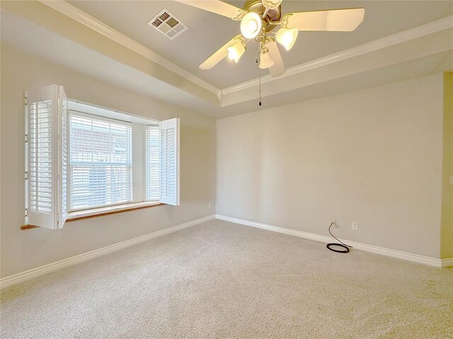 spare room with carpet flooring, a raised ceiling, visible vents, and baseboards