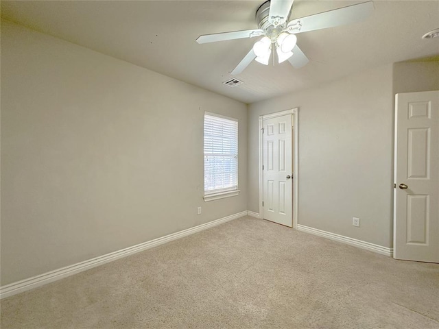 carpeted spare room featuring a ceiling fan, visible vents, and baseboards