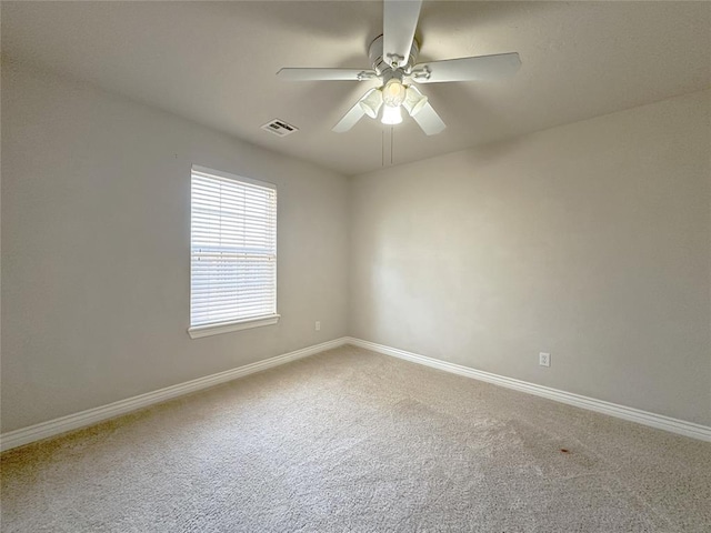 carpeted spare room featuring ceiling fan, visible vents, and baseboards