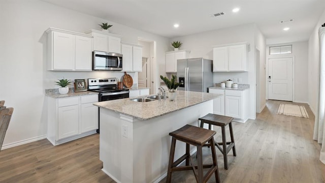 kitchen featuring light wood-type flooring, a breakfast bar area, stainless steel appliances, and a sink