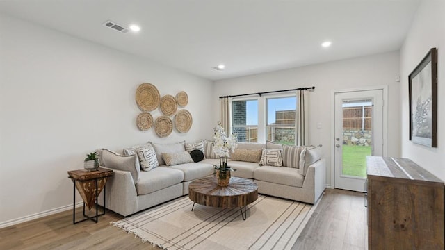 living room featuring light wood-type flooring, baseboards, and recessed lighting