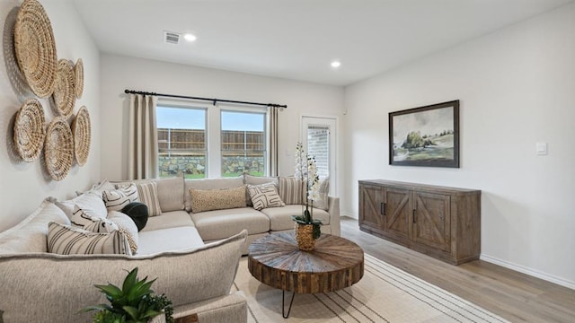 living room with recessed lighting, visible vents, light wood-style flooring, and baseboards