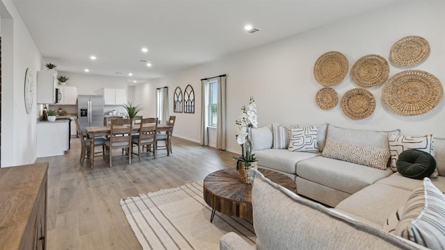 living room featuring baseboards, recessed lighting, and light wood-style floors