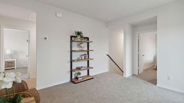 interior space with visible vents, carpet flooring, an upstairs landing, and baseboards