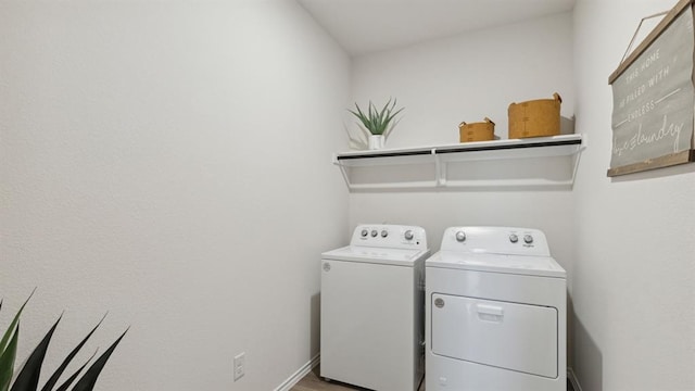 clothes washing area with laundry area, washing machine and dryer, and baseboards