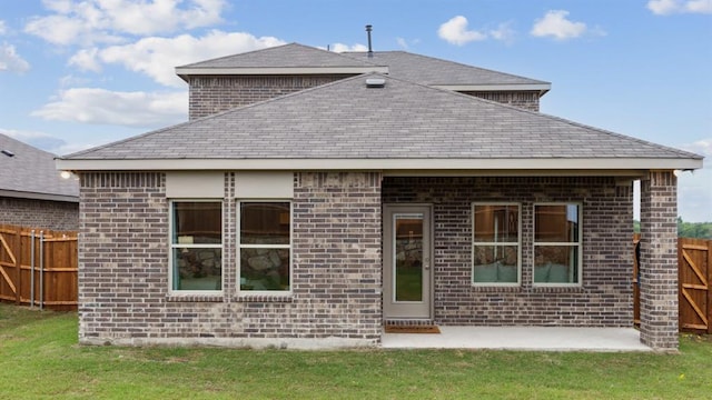 rear view of house featuring a yard, brick siding, and fence