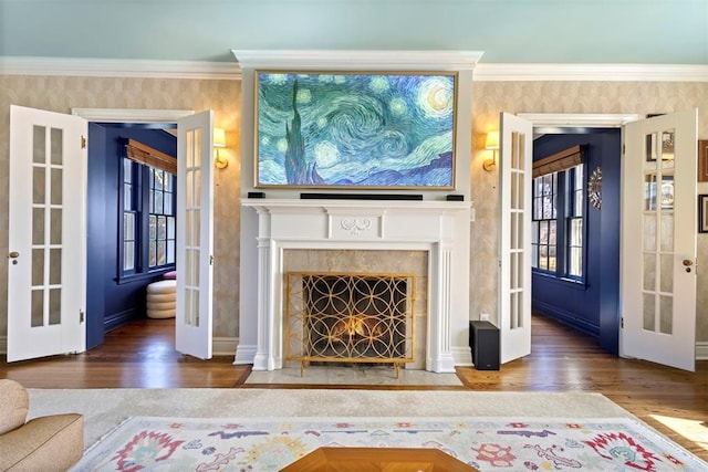 living room featuring a fireplace with flush hearth, french doors, ornamental molding, and wood finished floors