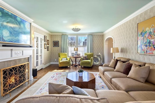 living room featuring wallpapered walls, ornamental molding, arched walkways, and wood finished floors