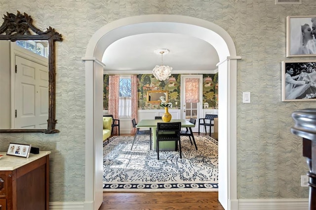 dining room with wallpapered walls, visible vents, arched walkways, and wood finished floors