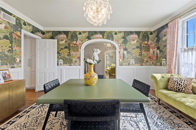 dining room featuring a wainscoted wall, ornamental molding, arched walkways, and wallpapered walls