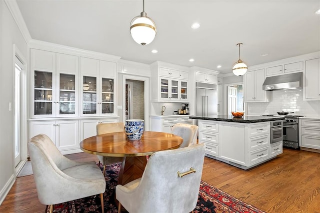 dining area with dark wood-type flooring, recessed lighting, and crown molding