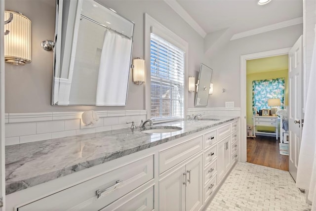 bathroom with ornamental molding, connected bathroom, a sink, and double vanity