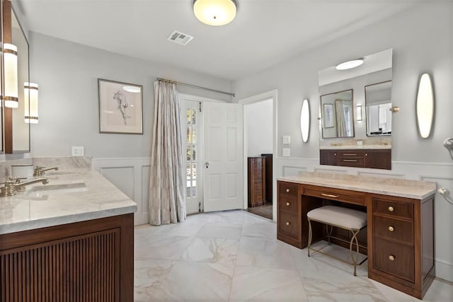 bathroom with visible vents, wainscoting, marble finish floor, vanity, and a decorative wall