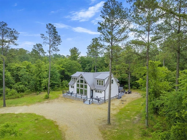 view of front of home with driveway and a view of trees