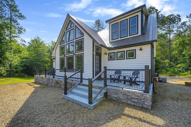 rear view of property featuring central AC unit and metal roof