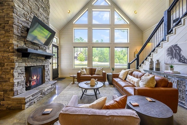 living room with high vaulted ceiling, a stone fireplace, wooden walls, and stairs