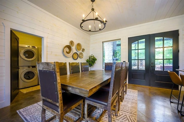 dining area with wooden ceiling, a notable chandelier, stacked washer / drying machine, french doors, and crown molding