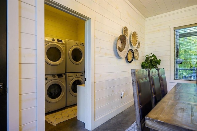 washroom featuring laundry area, stacked washer / drying machine, and wood walls