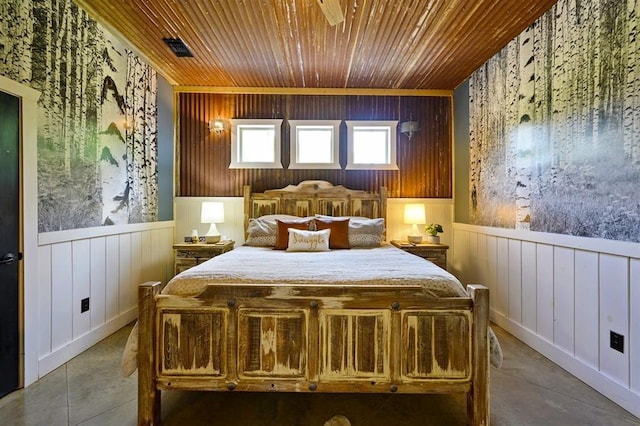 bedroom with wooden walls, wood ceiling, wainscoting, and visible vents