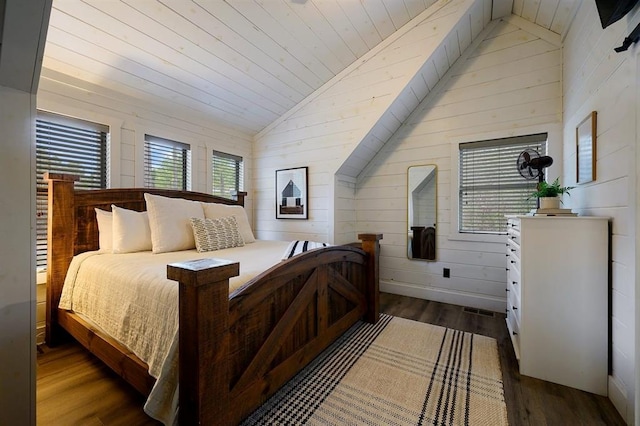 bedroom with lofted ceiling, dark wood-style floors, and wood walls