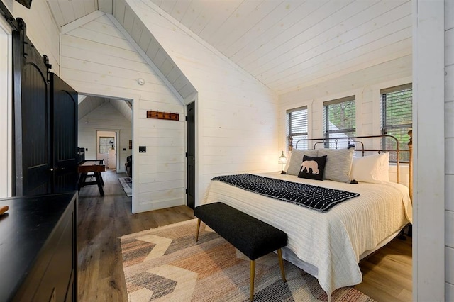 bedroom with lofted ceiling, wooden ceiling, a barn door, and wood finished floors