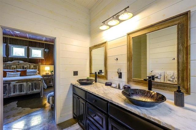 bathroom featuring double vanity, wood walls, a sink, and ensuite bathroom