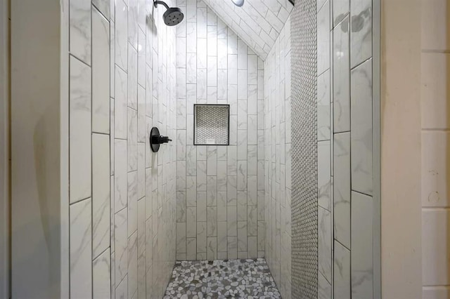 bathroom featuring vaulted ceiling and a tile shower