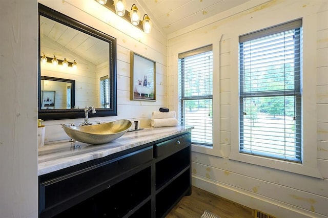 bathroom with lofted ceiling, baseboards, wood finished floors, and vanity