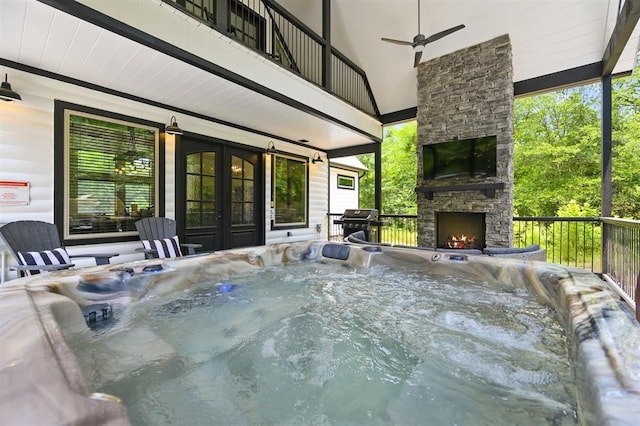 view of patio with an outdoor stone fireplace, french doors, a hot tub, a grill, and ceiling fan