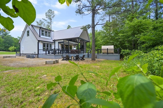 rear view of property with metal roof, a deck, and central AC unit