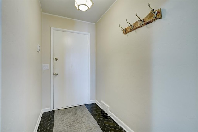 entryway with crown molding, visible vents, and baseboards