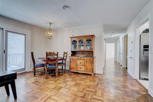 dining room with baseboards, visible vents, and a notable chandelier